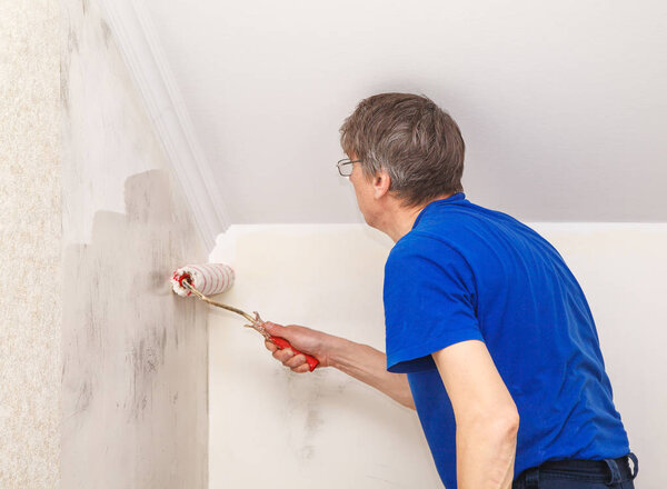 worker painting wall with glue 