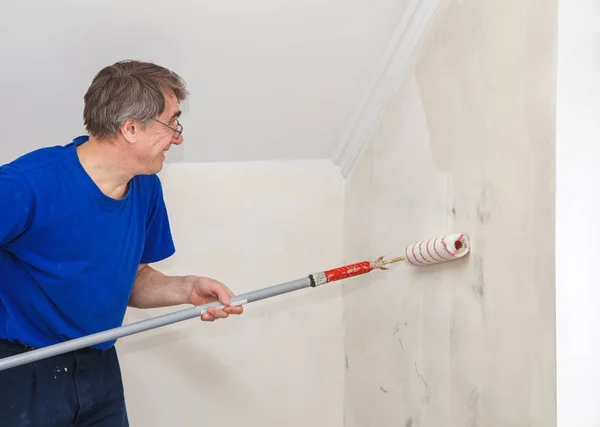 Viejo trabajador pintura pared con pegamento — Foto de Stock