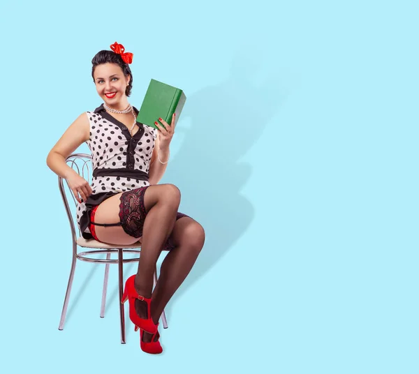 Mujer sonriente sentada en una silla con un libro —  Fotos de Stock