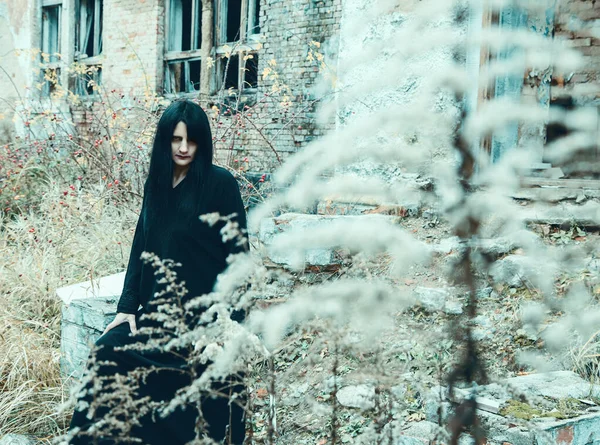 Жінка в чорній сукні, що стоїть біля зруйнованого будинку — стокове фото
