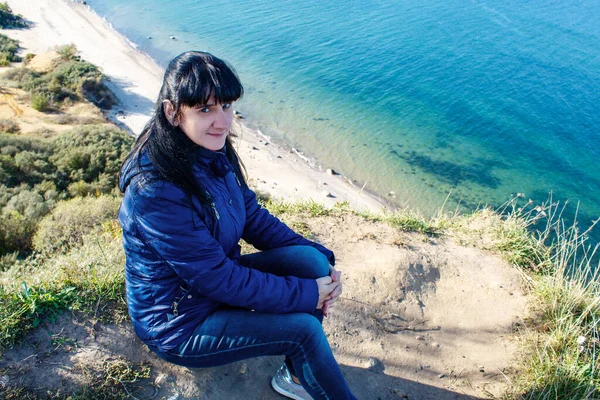 Jovem mulher sentada em uma costa alta — Fotografia de Stock