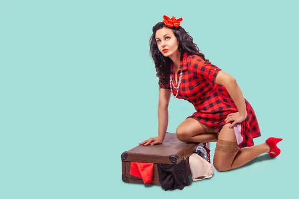Jonge vrouw zittend op de vloer en het zetten van kleren in een suitca — Stockfoto