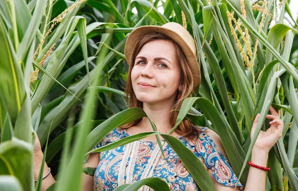 Portret van een jonge vrouw in een strohoed in een maïsveld — Stockfoto