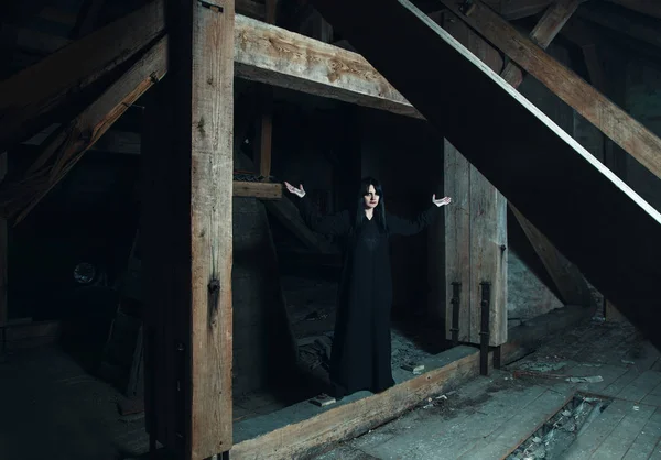 Gotická brunetka žena stojící v tmavé podkroví — Stock fotografie