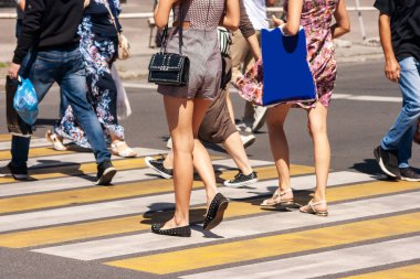 people crossing the street at pedestrian crossing on sunny summer day clipart