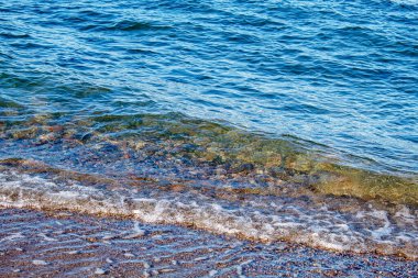 Açık mavi deniz dalgaları güneşli bir yaz gününde kıyıda