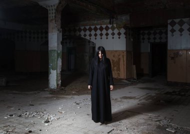 Gotik esmer kadın büyük, boş, kasvetli, terk edilmiş bir evde baş aşağı duruyor.