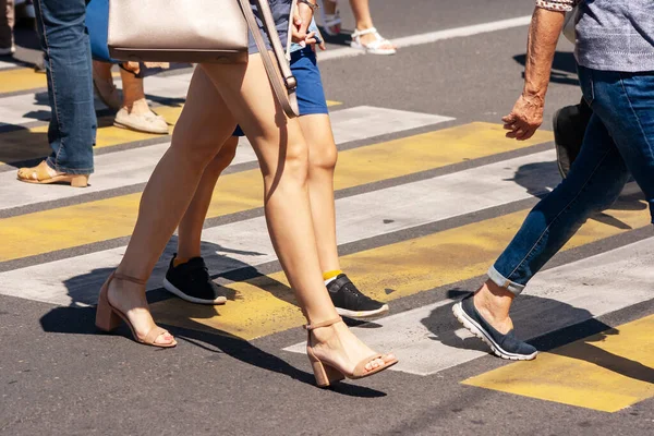 people crossing the street at pedestrian crossing on sunny summer day
