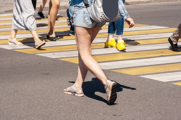 pedestrians crossing the road at a crosswalk in the city on sunny summer day