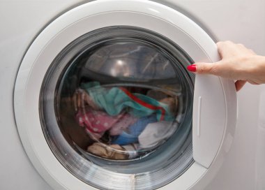 Çarşaflar çamaşır makinesine yüklendi. Kadın eli yakın çekim