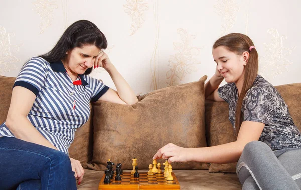 家のソファに座っている間にママと娘はチェスをする コロナウイルスの隔離 — ストック写真