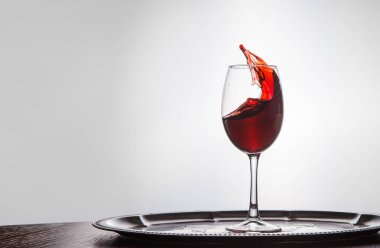 Kırmızı şarap, ahşap masanın üstünde duran bardaktan dökülür.