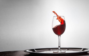 Kırmızı şarap arka plandaki bardaktan dökülür.
