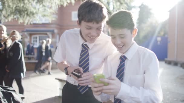 Meninos da escola olhando para telefones celulares — Vídeo de Stock