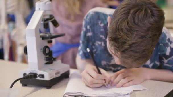 Мальчик смотрит в микроскоп — стоковое видео