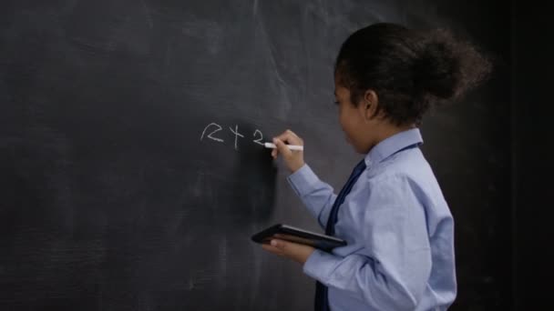 Jongen schrijven van wiskunde som op blackboard — Stockvideo
