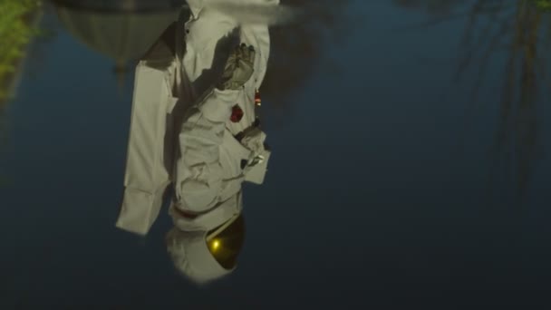 Астронавт смотрит на свое отражение в луже — стоковое видео