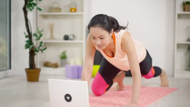 Woman using a laptop follow a workout — ストック動画
