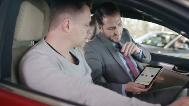 Vendedor mostrando al cliente el interior del coche nuevo — Vídeos de Stock