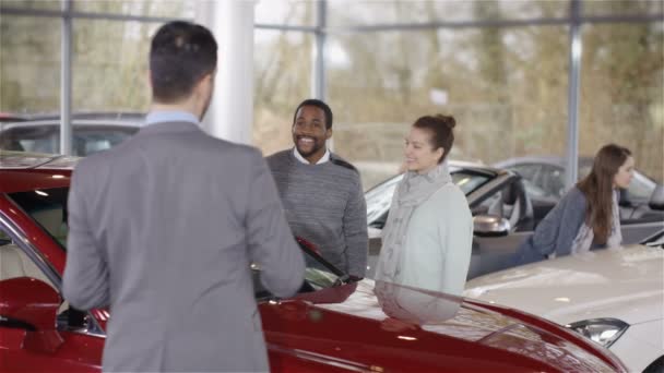 Salesman talking to customers in car dealership — Stock video