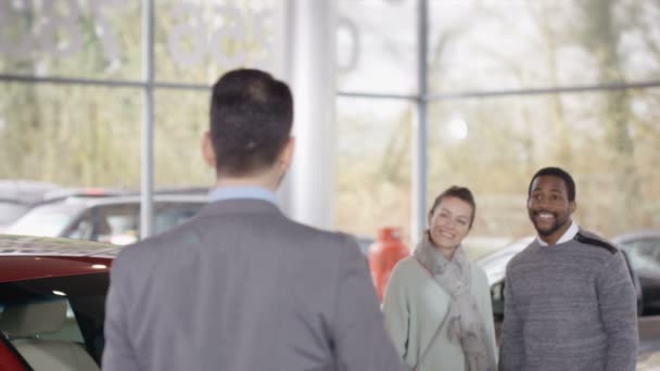 Salesman talking to customers in car dealership — Αρχείο Βίντεο