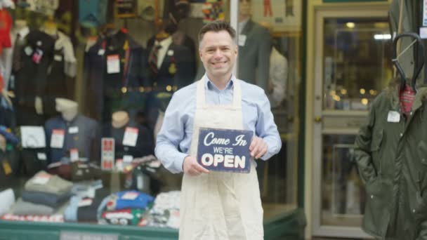 Happy shopkeeper holds up open sign — Stock Video