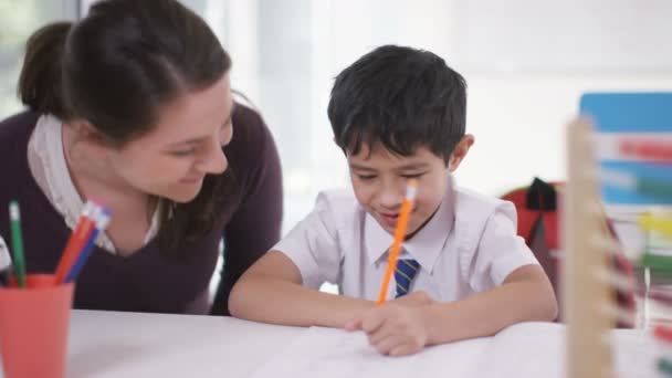 Хлопчик в класі отримує допомогу від вчителя — стокове відео