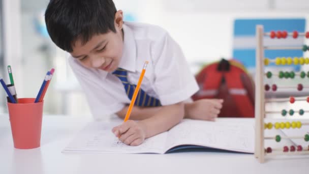 Маленький мальчик в классе пишет в тетрадке — стоковое видео