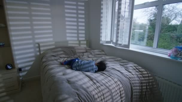 Хлопчик стрибає на ліжку — стокове відео