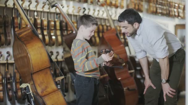 Apa és fia egy zenei áruházban vásárlás — Stock videók