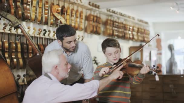 Père et fils regardant des violons — Video