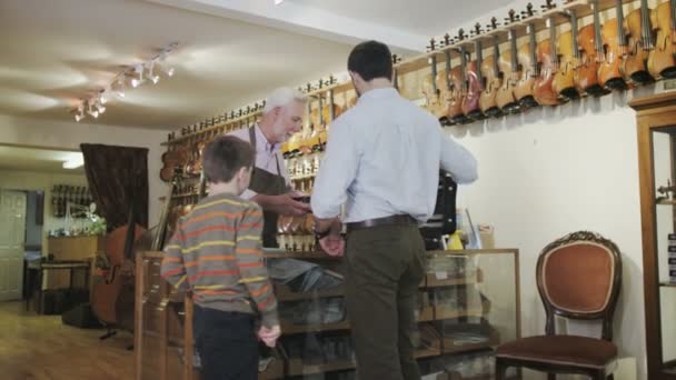 Father and son  looking at violins — Stock Video