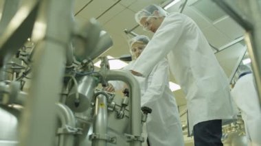 İşçiler fabrikada makine kontrol