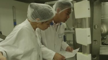 İşçiler fabrikada makine kontrol