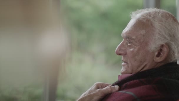 Hombre mayor sentado junto a la ventana — Vídeos de Stock