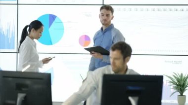 4 k iş takım tartışma, bilgisayar ve video duvara finansal verilere bakarak