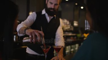 Gülümseyen barmen bayan müşterilere taze kokteyller hazırlıyor ve servis ediyor..
