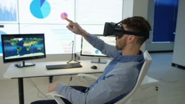 4k işadamı, fütüristik office sanal gerçeklik kulaklık ile etkileşim gösteren finansal bilgi ve Dünya Haritası bilgisayar ekranları