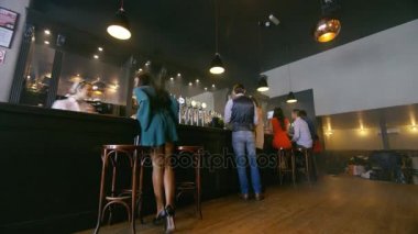 Yoğun şehir barında tipik bir vardiyada zaman kaybı, genç grup sosyalleşmesi ve bar çalışanları.