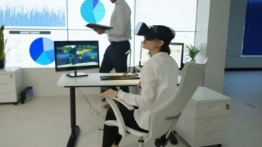 4k işkadını, fütüristik office sanal gerçeklik kulaklık ile etkileşim gösteren finansal bilgi ve Dünya Haritası bilgisayar ekranları