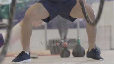 Çekici genç adam vücut geliştirme halatlar ile spor salonunda yerleştirmek.