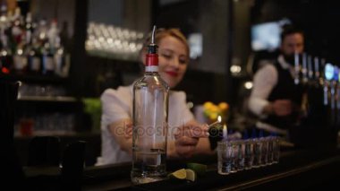 Gülümseyen barmen kibrit kullanarak bardakları saf likörle ateşe veriyor..