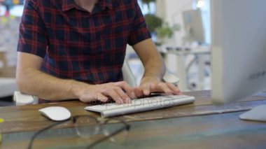 4k yaratıcı ofiste onun masasında bilgisayarda çalışan iş adamı