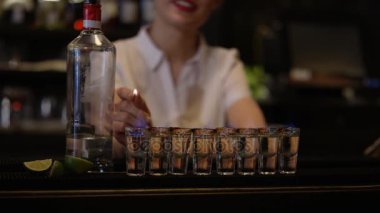 Gülümseyen barmen kibrit kullanarak bardakları saf likörle ateşe veriyor..