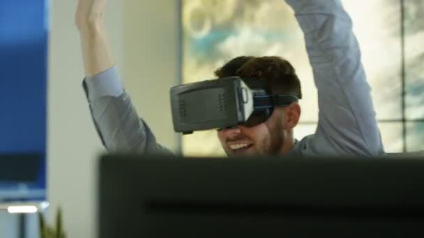 4K Ingénieur excité ou programmeur informatique portant une visionneuse de réalité virtuelle à son bureau avec graphique animé d'un tunnel de données en arrière-plan 