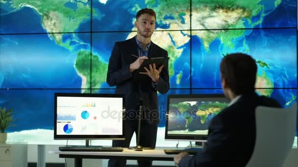 在视频墙上讨论大型世界地图图形的商家 在计算机屏幕上显示饼图和图形 — 图库视频影像