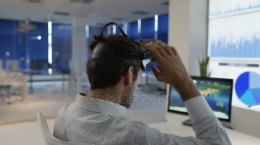 4k işadamı, fütüristik office sanal gerçeklik kulaklık ile etkileşim gösteren finansal bilgi ve Dünya Haritası bilgisayar ekranları