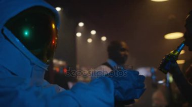 Unny astronaut relaxing in nightclub, drinking beer