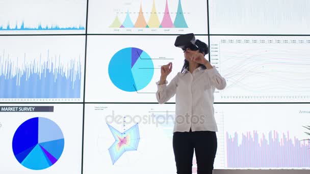 Бизнесвумен Взаимодействует Гарнитурой Виртуальной Реальности Перед Видеостеной Финансовыми Графиками — стоковое видео