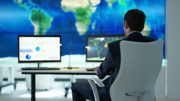 在办公室工作的商人与大世界地图图形上的视频墙和饼图和图形显示在计算机屏幕上 — 图库视频影像